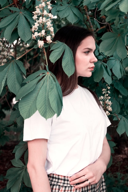 Jeune fille séduisante vêtements décontractés sur fond de feuilles de châtaignier. Concept de jeunesse, mode de vie, beauté naturelle.