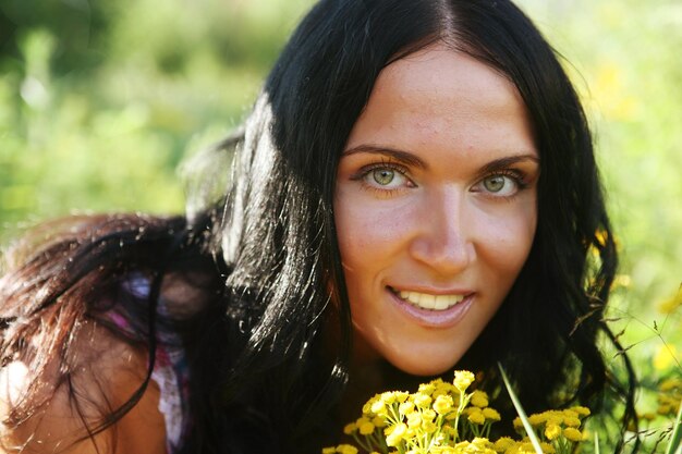 La jeune fille sent les fleurs jaunes dans le champ