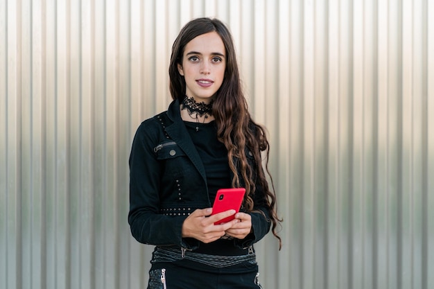 Jeune fille avec un smartphone à la main souriant tout en regardant la caméra