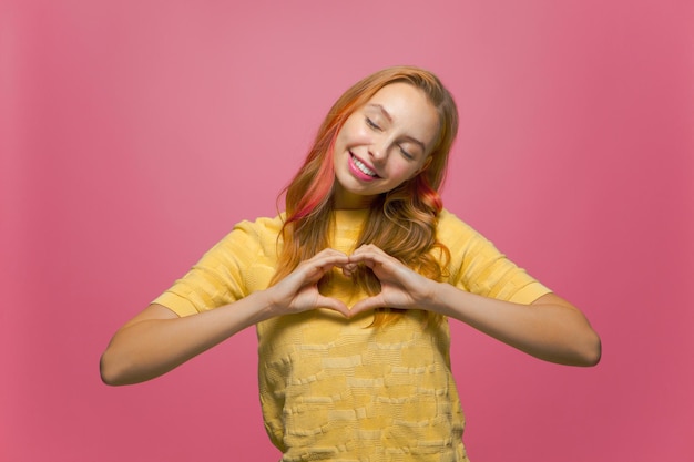 Une jeune fille souriante et amicale fait un geste cardiaque signe d'amour concept de don de charité de bien