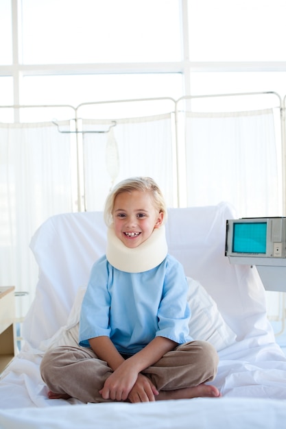 Jeune fille souriante assise sur un lit d&#39;hôpital