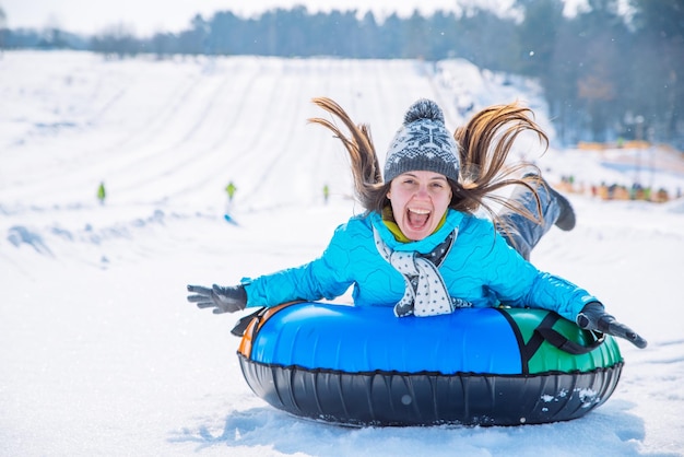 Jeune fille souriante balade en traîneau à neige activités hivernales sur la colline