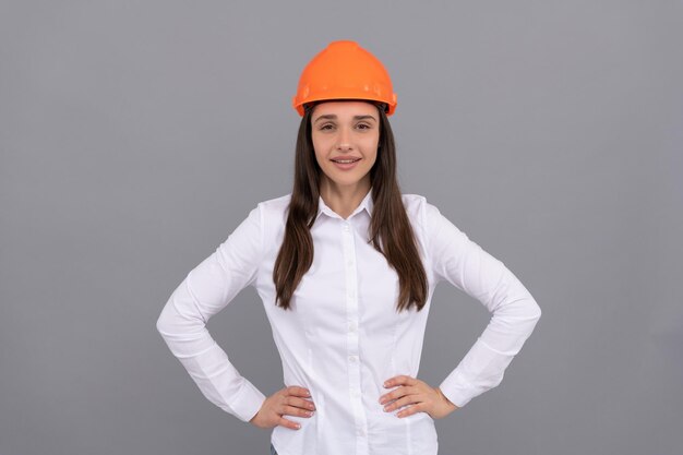 Jeune fille souriante en casque de sécurité et chemise blanche, ouvrier