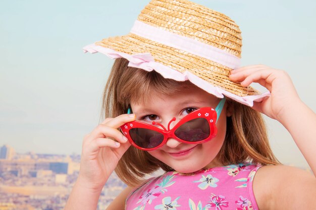 Jeune fille souriante avec chapeau de paille et lunettes de soleil avec paris en arrière-plan