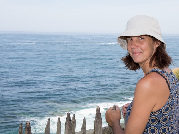Jeune fille souriante dans un chapeau blanc souriant au front de mer d'été