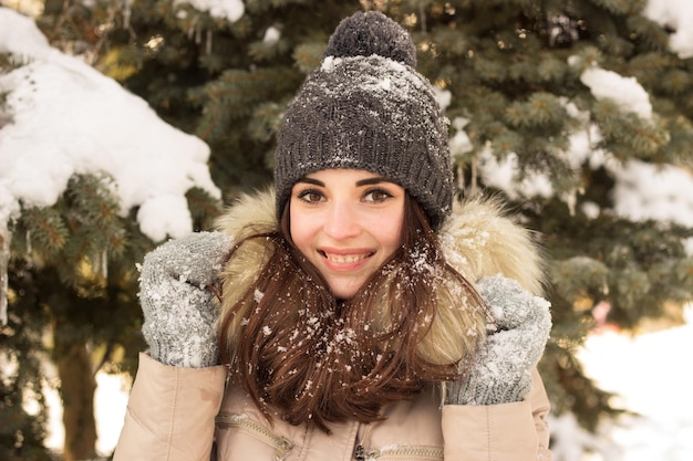 Jeune fille souriante dans le parc en hiver avec beaucoup de neige autour