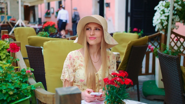 Jeune fille souriante dans un restaurant extérieur joyeuse jeune femme assise à table dans un restaurant extérieur dans une rue confortable