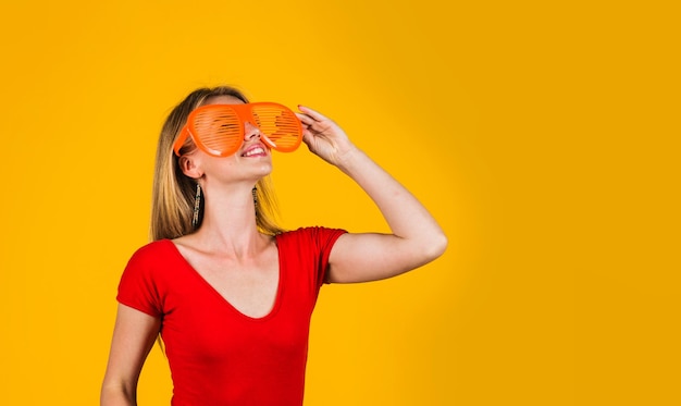 Jeune fille souriante dans des verres drôles regardant quelque chose de publicité et d'espace de copie de réduction