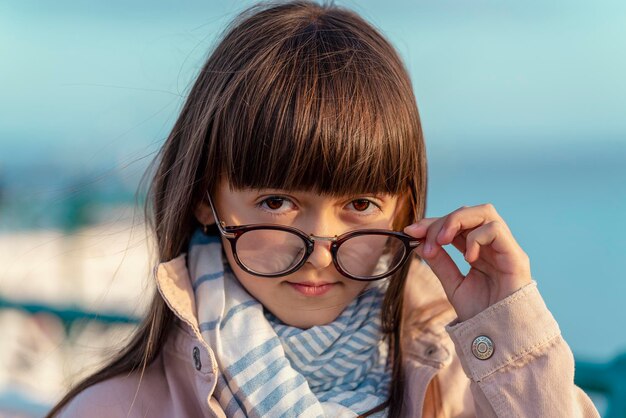 Une jeune fille souriante debout sur la jetée en regardant la mer au coucher du soleil