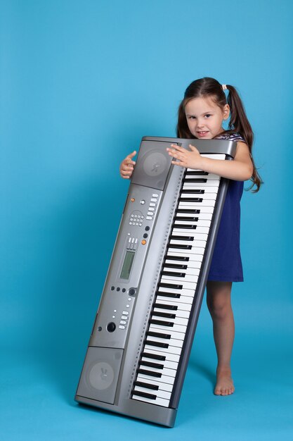 Jeune fille souriante embrassant un synthétiseur électronique vertical