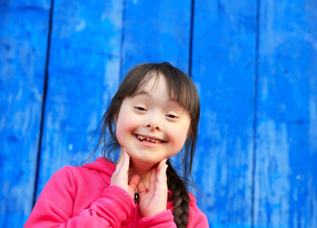 Jeune fille souriante sur fond de mur bleu.