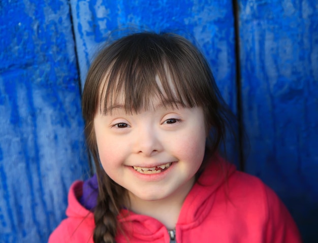 Jeune fille souriante sur fond de mur bleu.