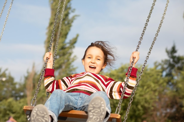 Jeune fille souriante jouant sur une balançoire en plein air Activité estivale pour enfants