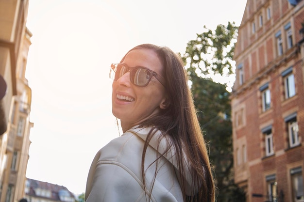 Jeune fille souriante et joyeuse dans des verres à l'extérieur de la ville