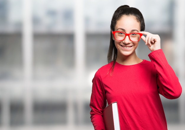 Jeune fille souriante avec des lunettes tenant un livre, copie-espace sur sa gauche