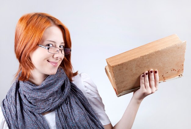 Jeune fille souriante de mode dans des verres avec livre d'âge.