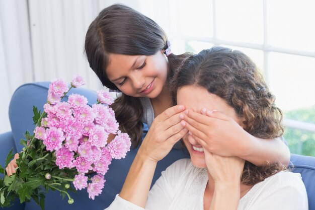 Jeune fille souriante offrant des fleurs à sa mère