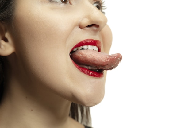 Jeune fille souriante ouvrant la bouche et montrant la longue et grosse langue géante sur blanc.