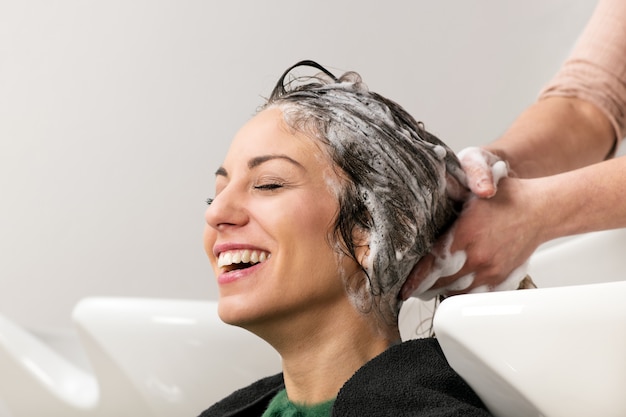 Jeune fille souriante pendant qu'elle se lave les cheveux