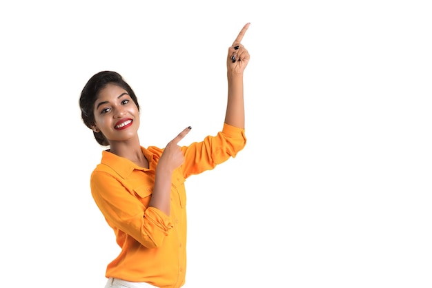 Jeune fille souriante pointant du doigt pour copier l'espace sur un fond blanc