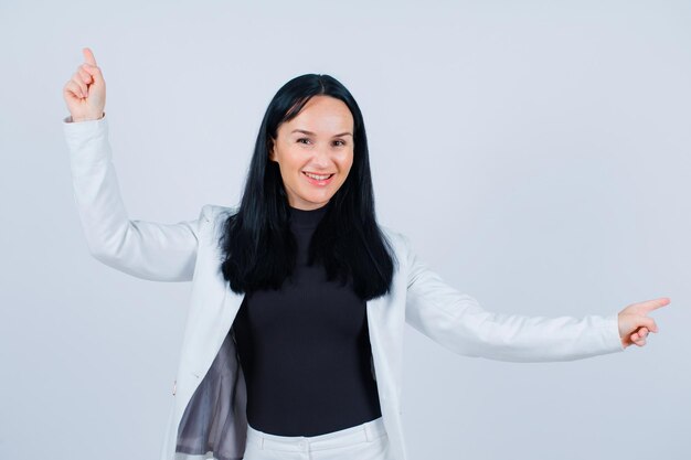 Jeune fille souriante pointe vers le haut et à droite avec les index sur fond blanc