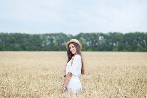 Jeune fille souriante en robe blanche et chapeau de paille