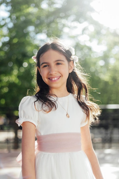 Jeune fille souriante en robe de communion à l'extérieur