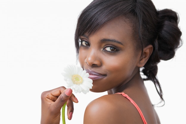 Jeune fille souriante, sentant la marguerite