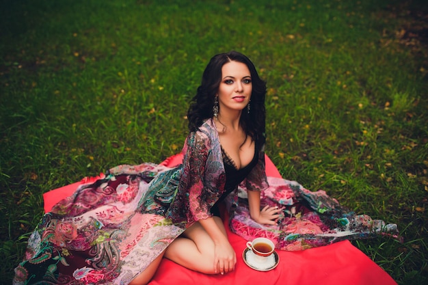 Jeune fille souriante avec une tasse dans ses mains. Fille buvant du thé.