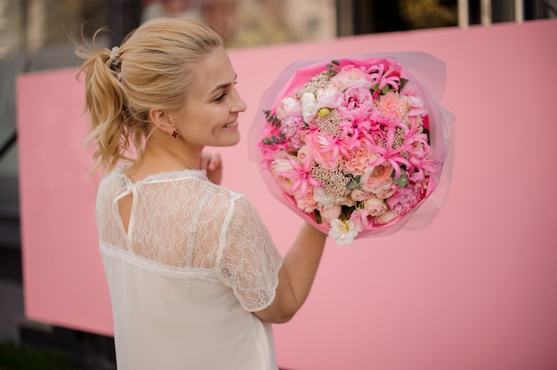Jeune fille souriante tenant un bouquet de printemps de tendres fleurs roses et blanches