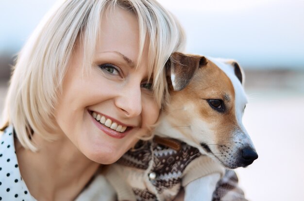 Une jeune fille souriante tient son chien Jack Russell Terrier dans ses bras