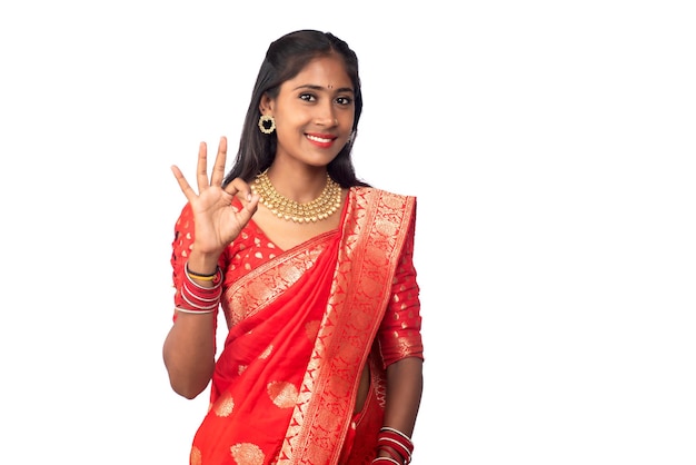 Jeune fille souriante traditionnelle montrant le signe ok ou le pouce levé sur fond blanc