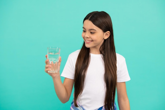 Jeune fille souriante va boire une boisson saine enfance mode de vie équilibre hydrique dans le corps boire par jour hydratation vitalité être hydraté enfant tenir un verre d'eau minérale enfant avoir soif