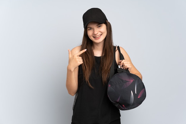 Jeune fille de sport avec sac de sport isolé sur gris donnant un geste de pouce en l'air