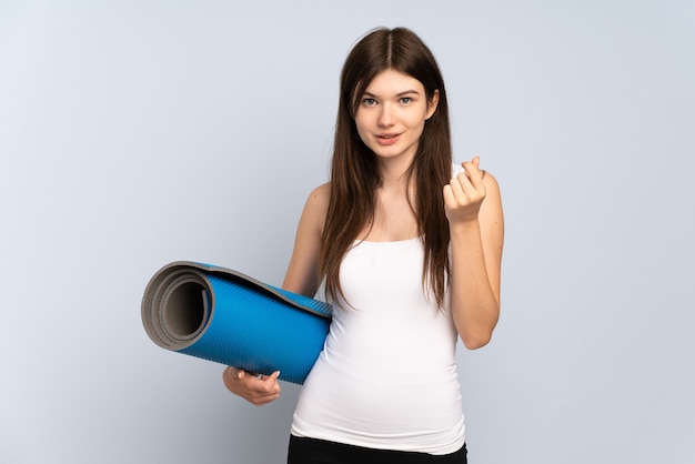 Jeune fille sportive allant à des cours de yoga tout en tenant un tapis faisant de l'argent