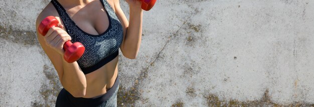 Une jeune fille sportive mince en tenue de sport exécute une série d'exercices sur fond de montagnes