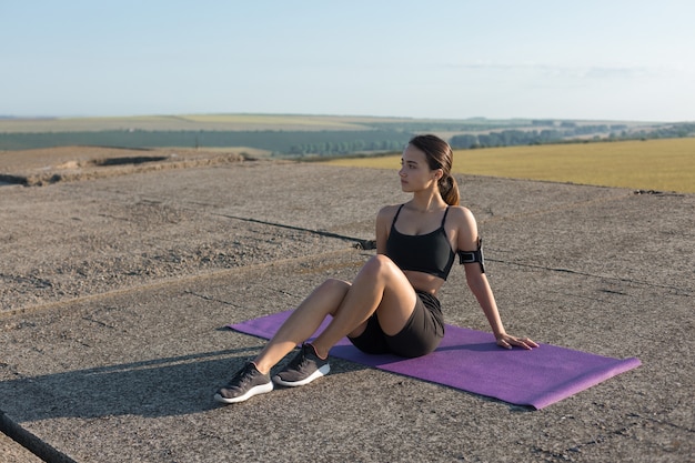 Une jeune fille sportive mince en tenue de sport avec des imprimés en peau de serpent effectue une série d'exercices