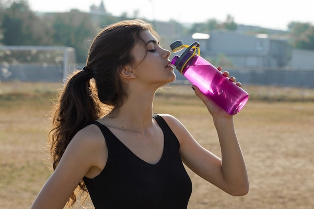 Une jeune fille sportive mince en tenue de sport avec des imprimés en peau de serpent effectue une série d'exercices