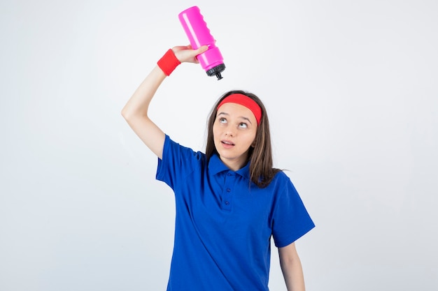 une jeune fille sportive tenant une bouteille d'eau rose.