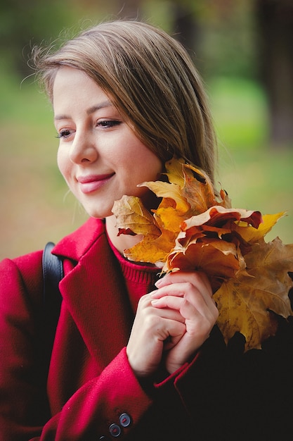 Jeune fille de style avec des feuilles dans l'allée du parc