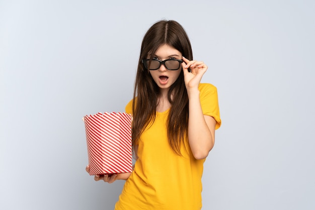 Jeune fille surprise avec des lunettes 3d et tenant un grand seau de pop-corn