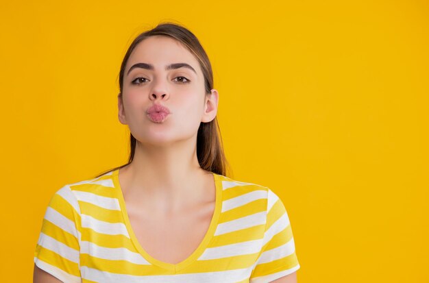 Jeune fille en t-shirt rayé d'été sur fond jaune baiser