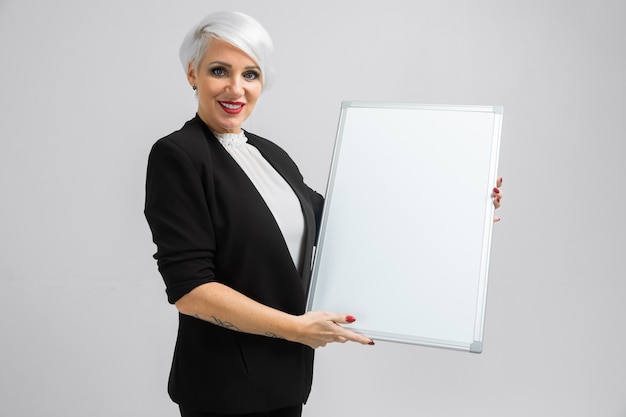 Jeune fille avec un tableau magnétique dans ses mains se tient isolé