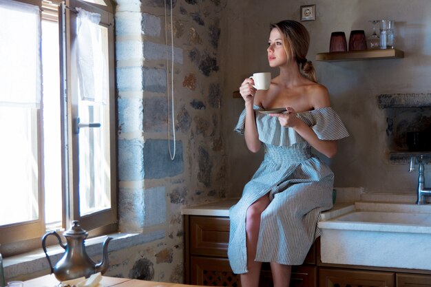 Jeune fille avec une tasse de café ou de thé dans la cuisine grecque