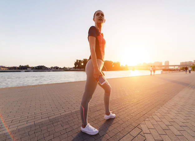 Une jeune fille avec un téléphone dans les mains s'est arrêtée pendant le jogging du soir