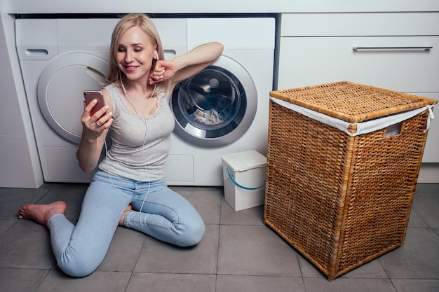 Jeune fille avec un téléphone dans le panier à linge sale blanchisserie