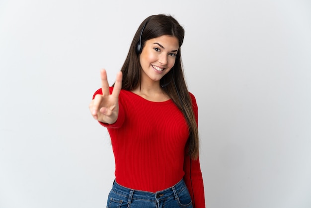 Jeune fille de télévendeur brésilien sur mur isolé souriant et montrant le signe de la victoire