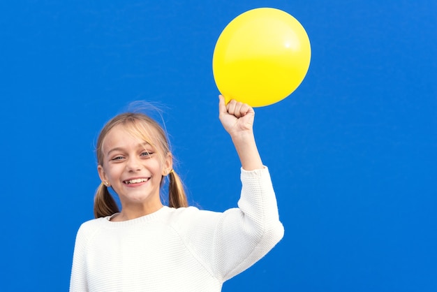 Jeune fille tenant un ballon jaune