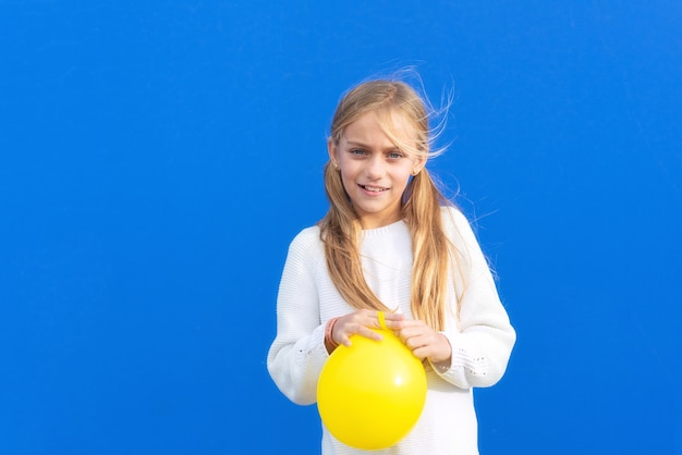 Jeune fille tenant un ballon jaune