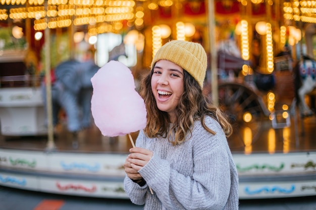 Photo jeune fille tenant une barbe à papa et souriant